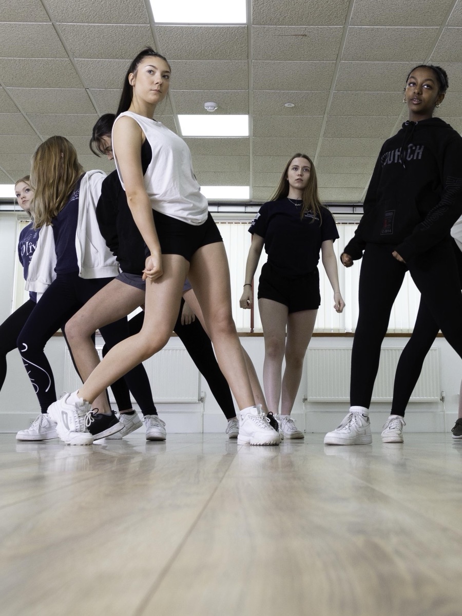 Dance students mid-routine in a performing-arts academy studio